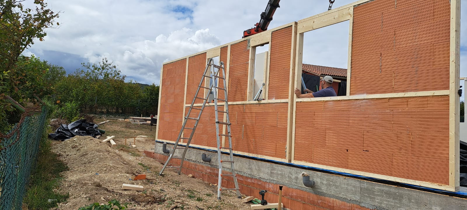 Ensamblaje en obra de otro muro AKABRICK, operario guiando el panel cerámico hasta su posición