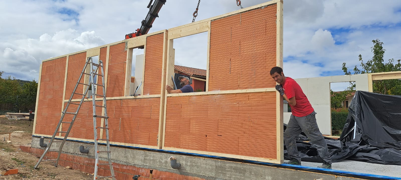 Montaje en obra de un muro AKABRICK: panel de ladrillo Megabrick izado con grúa sobre la cimentación